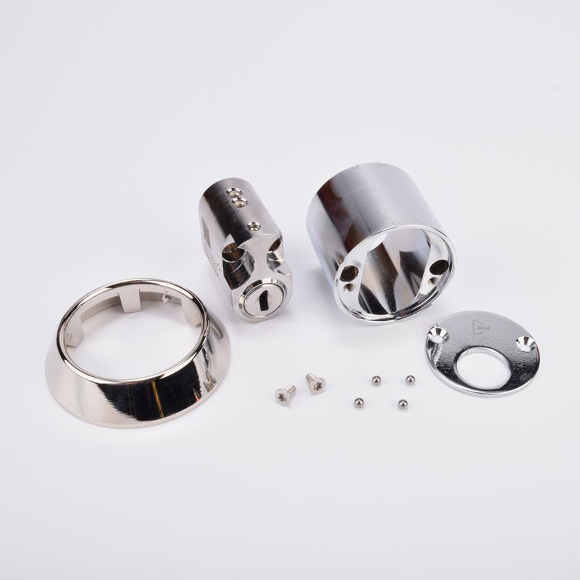 Kromad låssats med cylinder, två täckhylsor, täckbricka och små skruvar.