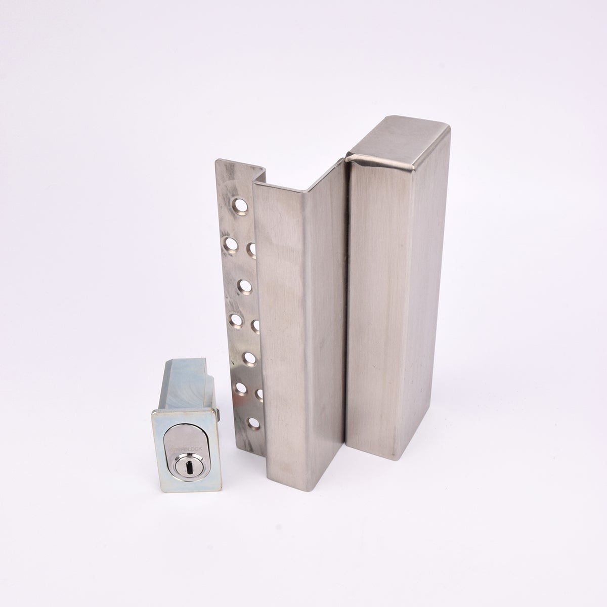 Två metallföremål visas. Det större är en L-formad nyckelförvaringsenhet med flera cirkulära hål längs ena sidan. Det mindre är en rektangulär cylinderhållare med en oval cylinder.