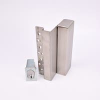 Två metallföremål visas. Det större är en L-formad nyckelförvaringsenhet med flera cirkulära hål längs ena sidan. Det mindre är en rektangulär cylinderhållare med en oval cylinder.