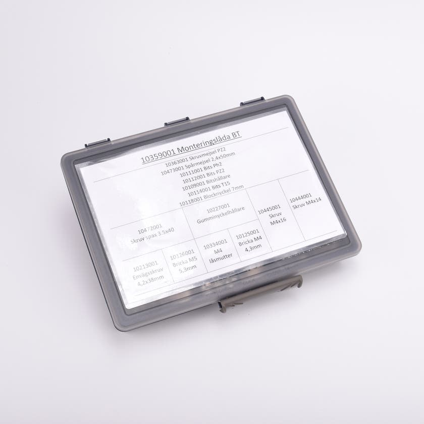 En grå sortimentslåda täckt med en vit översikt med vad som ligger i de olika facken.