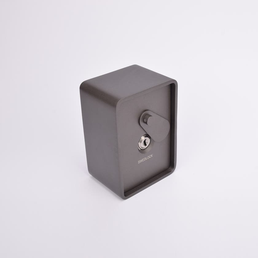 Grått fasadnyckelskåp i metall med rundade hörn och vridbar skyddskåpa.