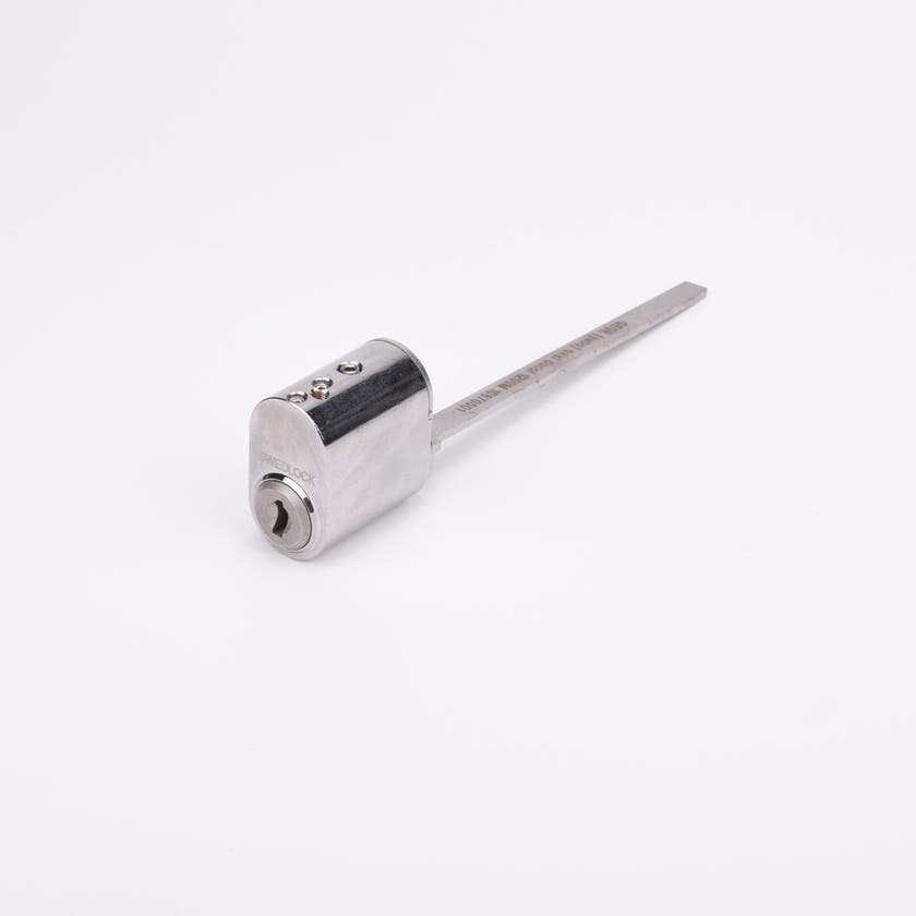 Oval låscylinder i silverfärgad metall med en lång, platt, räfflad metall medbringare.