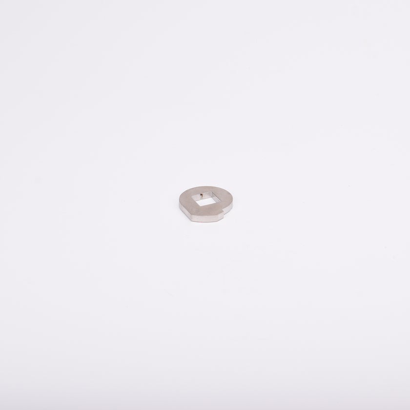 Metallbricka med cirkulär form och fyrkantigt hål i mitten.