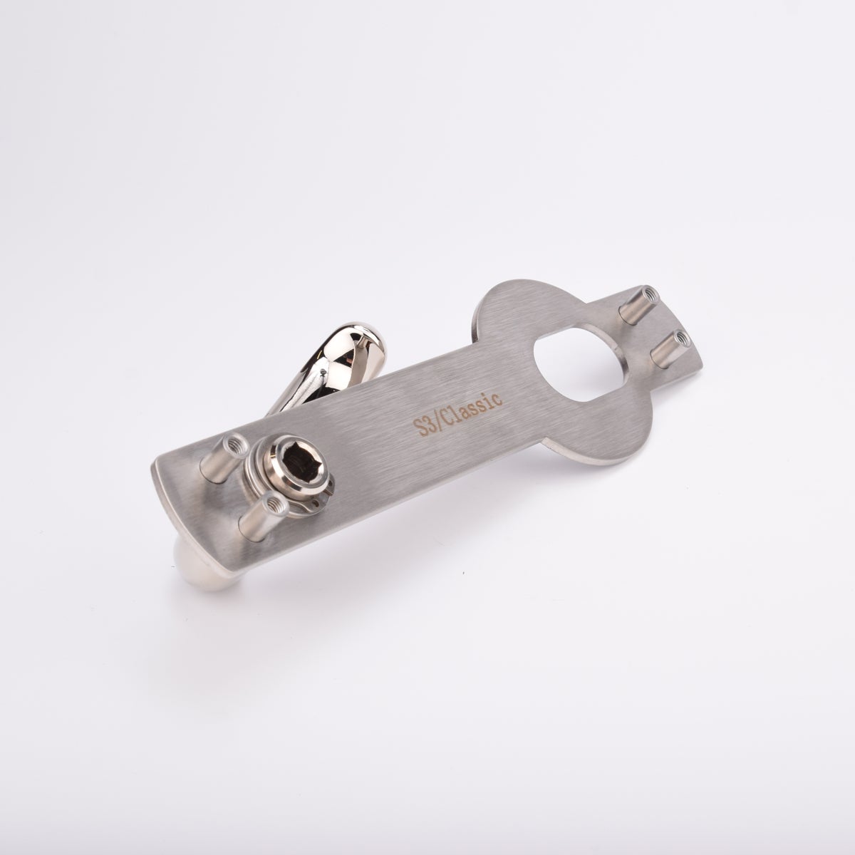 Blankt metallhandtag monterat på rektangulär platta med två skruvhål och ett ovalt hål.