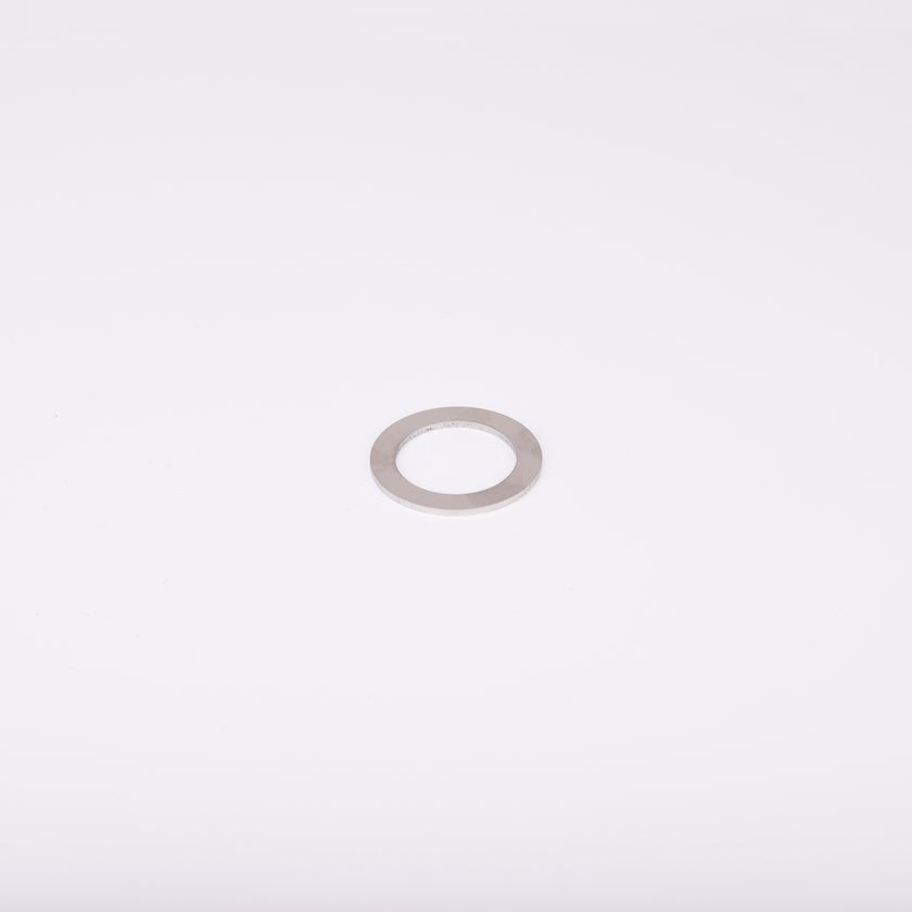 En distansbricka i metall med cirkulär form och ett centralt hål.