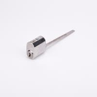 Oval låscylinder i silverfärgad metall med en lång, platt, räfflad metall medbringare.