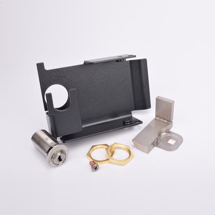 Uppsättning låskomponenter: metallfäste med cirkulär öppning, cylindrisk låskolv, två mässingsmuttrar och vinklad metallplatta.