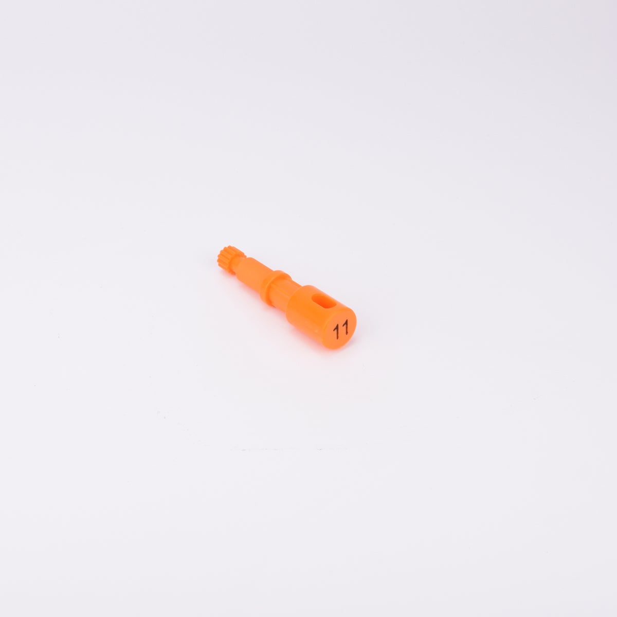 Orange användarpegg med cylindrisk form och flera sektioner med olika diameter. Ena änden är ihålig med ett avlångt spår, medan den motsatta änden har en räfflad yta.
