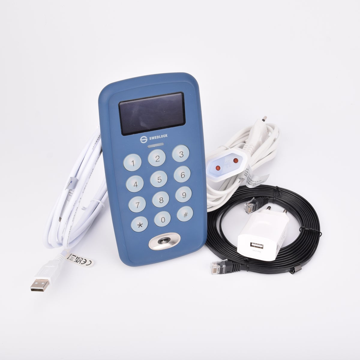 Blå elektronisk nyckeluppdateringsenhet med tangentbord, med liten skärm upptill och märkning "SafeNet", omgiven av USB-kabel, Ethernetkabel, strömadapter.