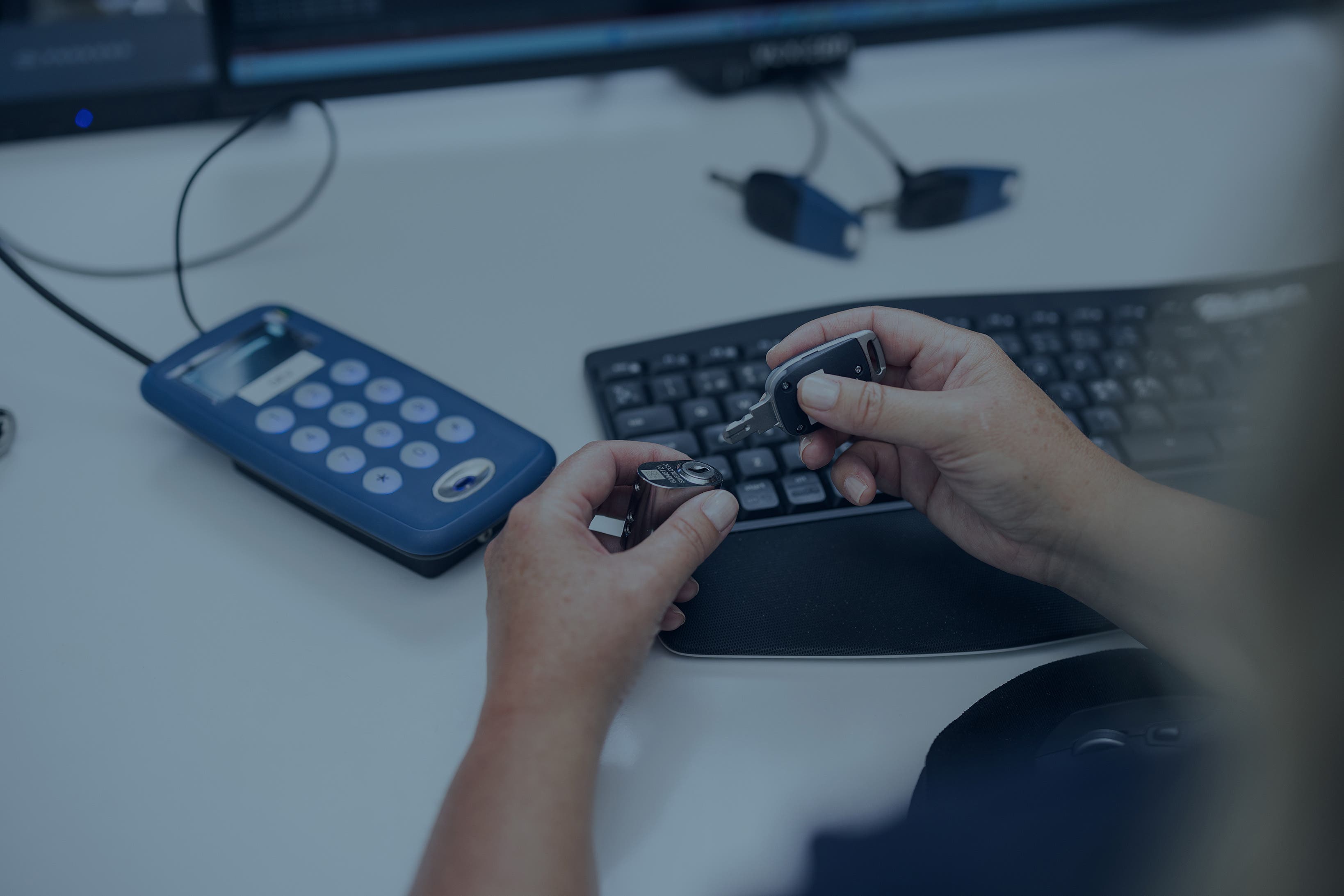 Två händer som håller en nyckel, i bakgrunden är nyckeluppdaterare