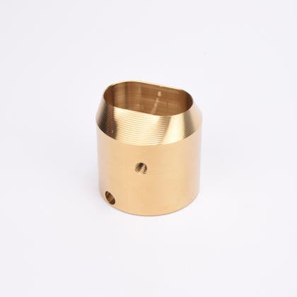 Mässingsfärgat utfyllnadsadapter i metall med snedskuren topp som bildar en oval öppning.