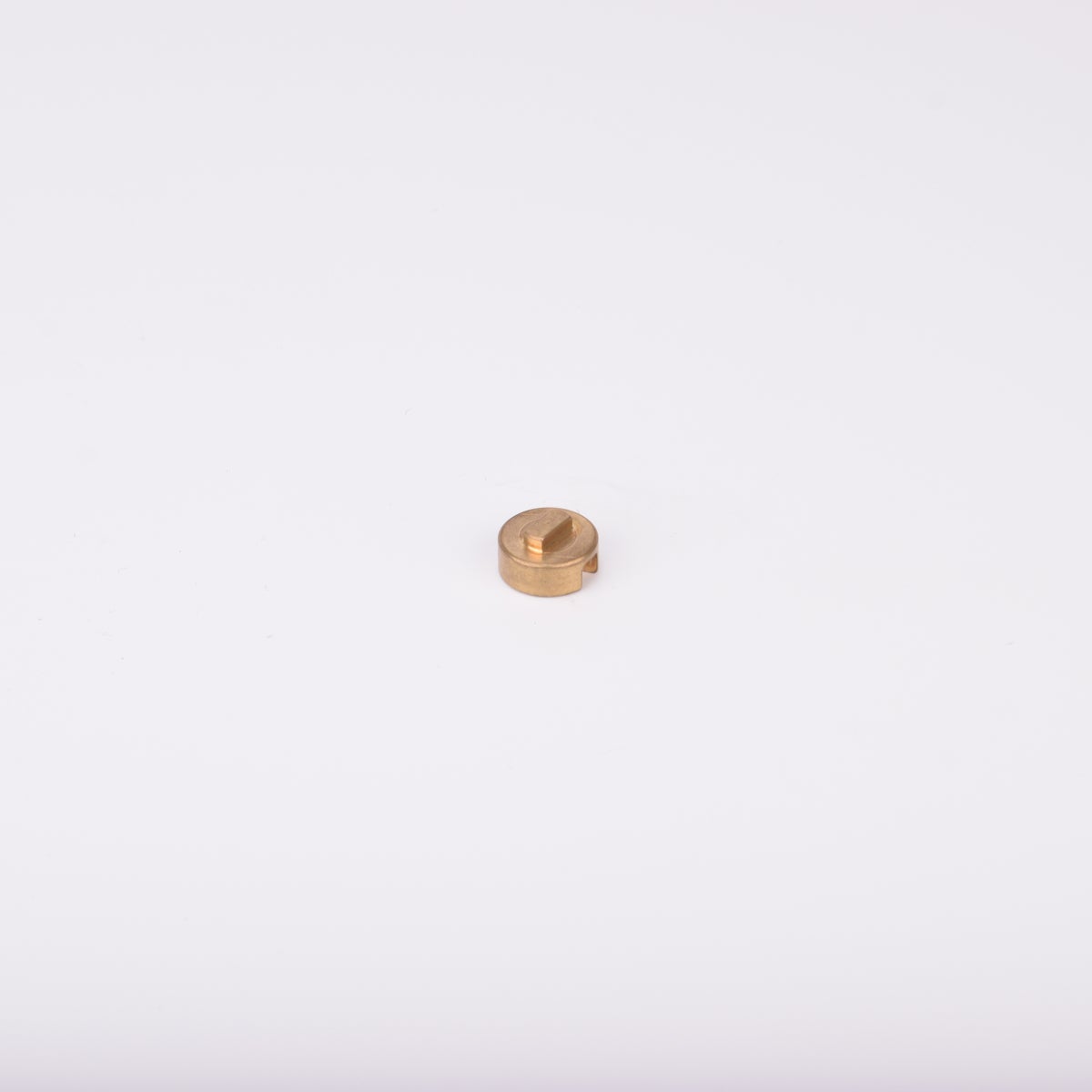 Liten rund adapter i metall med upphöjd rektangulär sektion på ovansidan.
