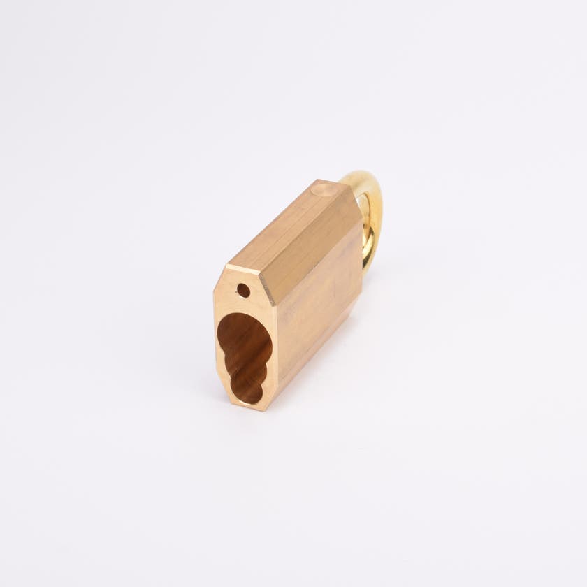 Mässingsfärgat hänglås med rektangulär kropp och rund bygel samt nyckelhålsformat hål i på kanten.