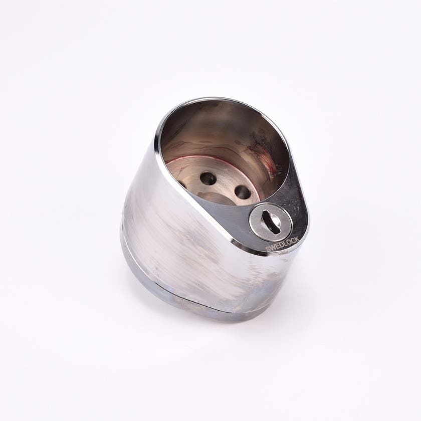 Droppformat metallhus med runt urtag för låscylinder, samt nyckelhål.