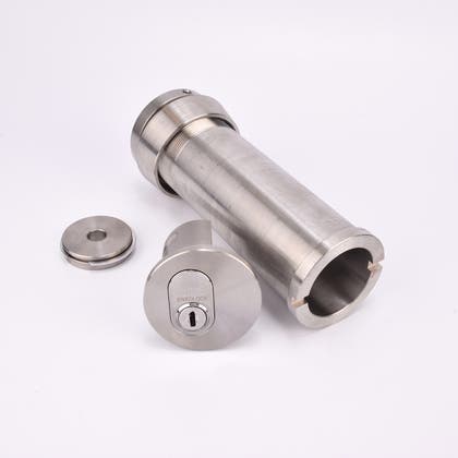 Cylindrisk silverfärgat nyckelfacksrör samt ett runt lås och en rund bricka.