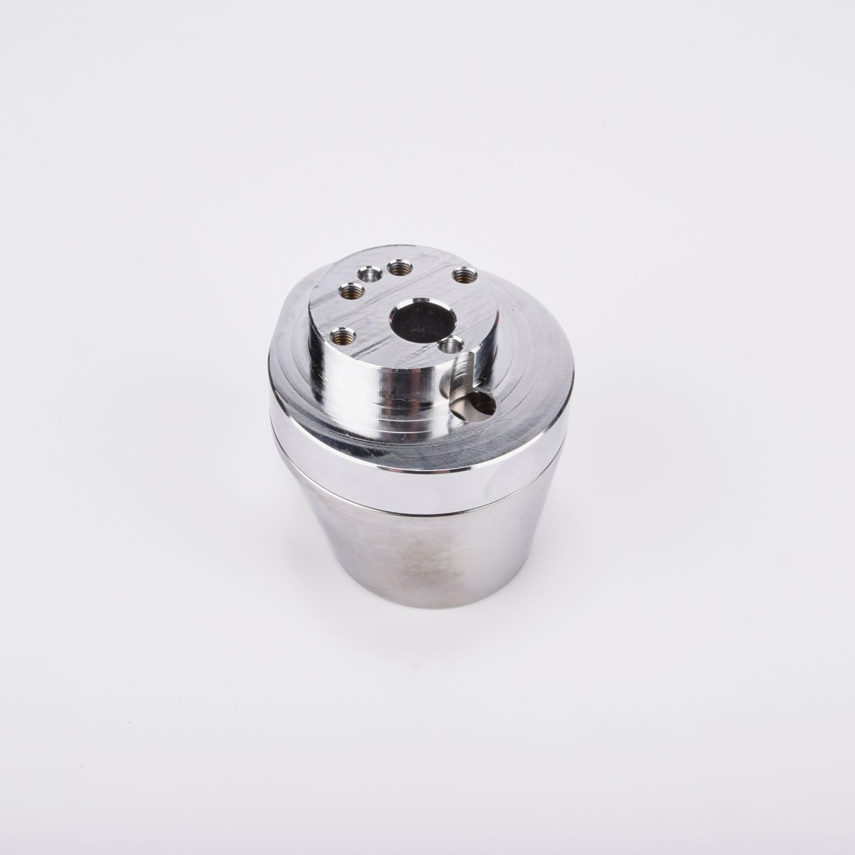 Silverfärgad metallkropp med rundad bas och flera hål på ovansidan.