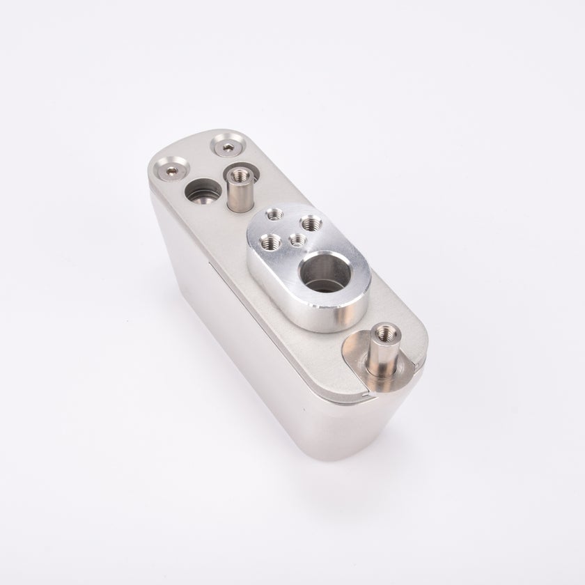 Rektangulär metallkomponent med flera gängade hål och monteringsfästen.