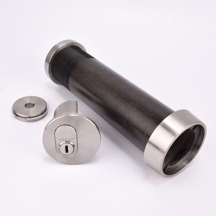 Cylindrisk nyckelfacksrör med svart kropp och silverfärgade ändar, samt ett runt lås och en rund bricka.