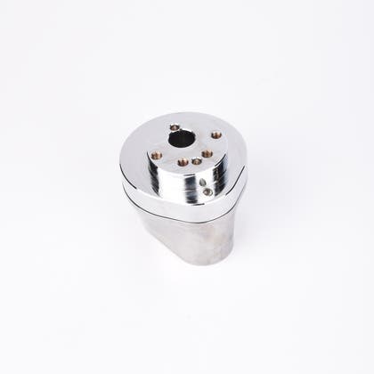 Silverfärgad metallkropp med rundad bas och flera hål på ovansidan.