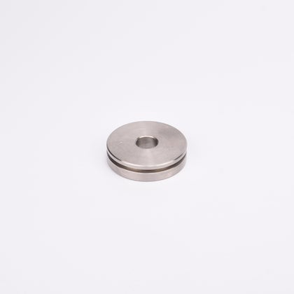 Rund metallskiva med centralt hål och spår längs med kanten.