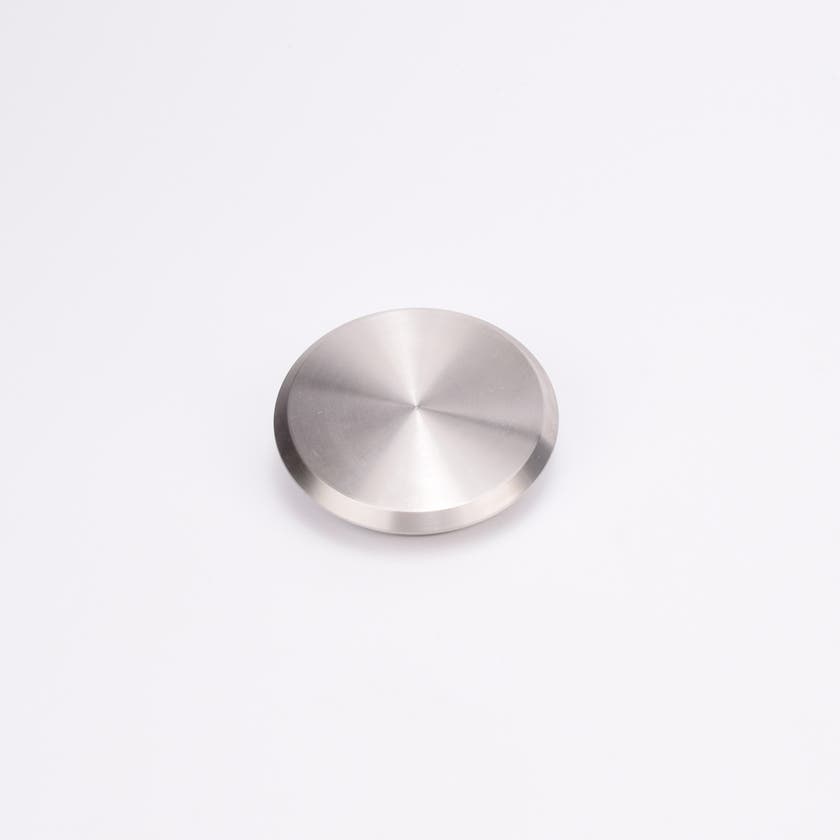 Metallisk, cirkulärt täcklock med slät, reflekterande yta.