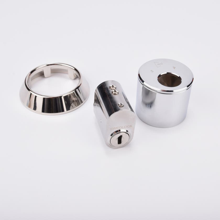 Låssats i krom med cylinder och tre runda täckhylsor.