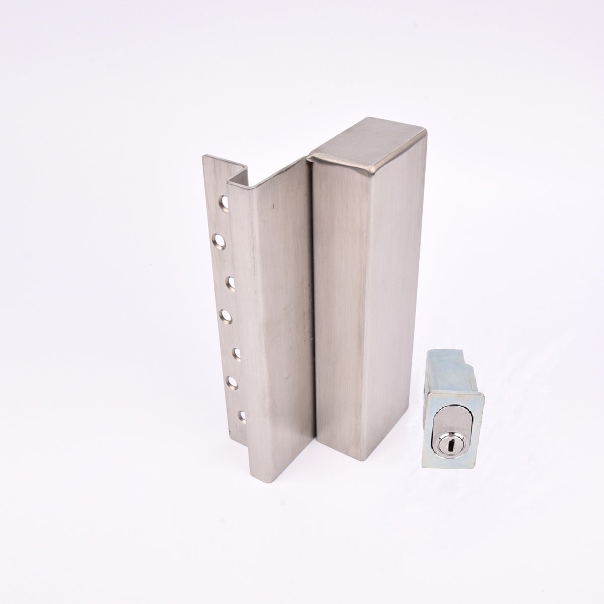 Två metallföremål visas. Det större är en L-formad nyckelförvaringsenhet med flera cirkulära hål längs ena sidan. Det mindre är en rektangulär cylinderhållare med en oval cylinder.