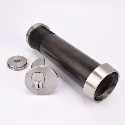 Cylindrisk nyckelfacksrör med svart kropp och silverfärgade ändar, samt ett runt lås och en rund bricka.
