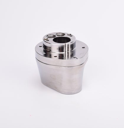 Silverfärgad metallkropp med rundad bas och flera hål på ovansidan.