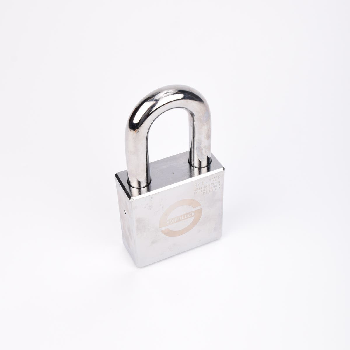 Silverfärgat Svedlock‑hänglås i metall med rund, robust bygel och graverad märkning på framsidan.