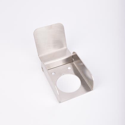 Väggmonterad väderskydd i rostfritt stål med cirkulärt urtag och två skruvhål, avsedd för cylinderformad produkt.