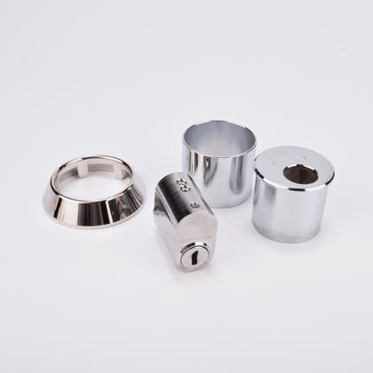 Låssats i krom med cylinder och tre runda täckhylsor.