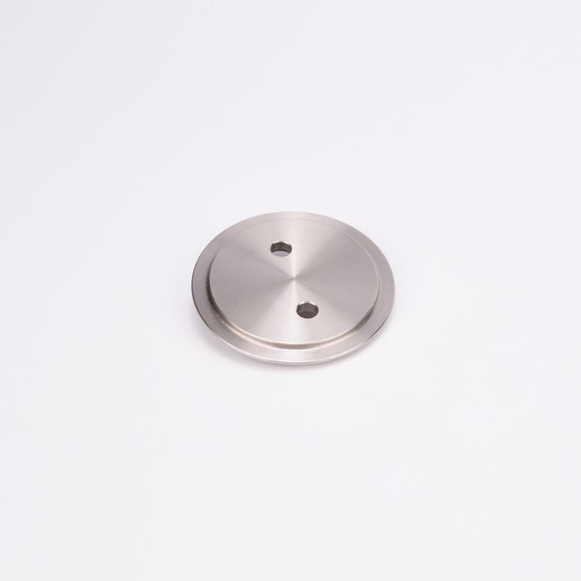 Metallisk, cirkulärt täcklock med slät, reflekterande yta och två jämnt placerade hål nära mitten.