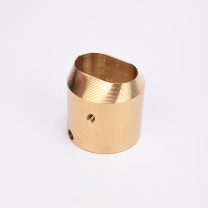 Cylindrisk mässingslås med runt sidohål och avfasad topp med oregelbunden öppning.