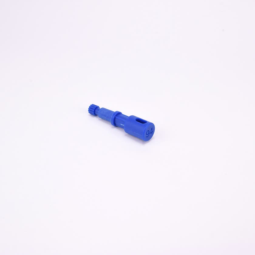 Blå användarpegg med cylindrisk form och flera sektioner med olika diameter. Ena änden är ihålig med ett avlångt spår, medan den motsatta änden har en räfflad yta.