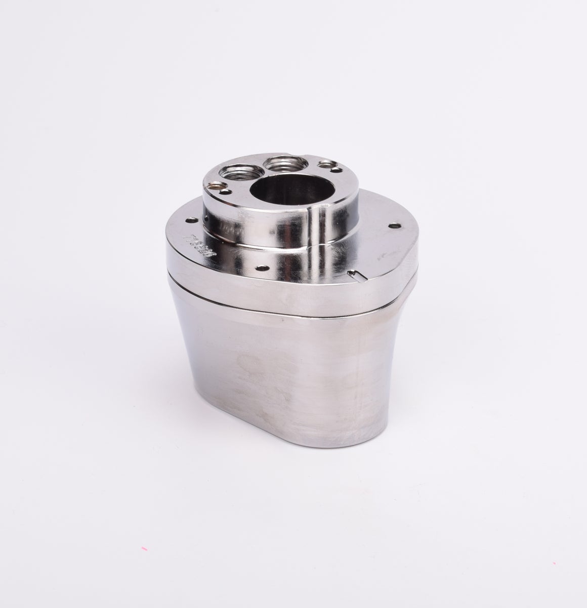 Silverfärgad metallkropp med rundad bas och flera hål på ovansidan.