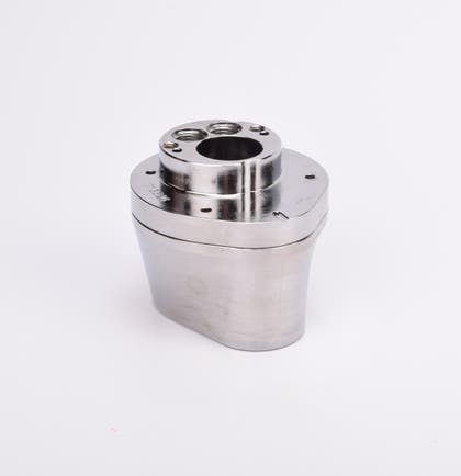 Silverfärgad metallkropp med rundad bas och flera hål på ovansidan.