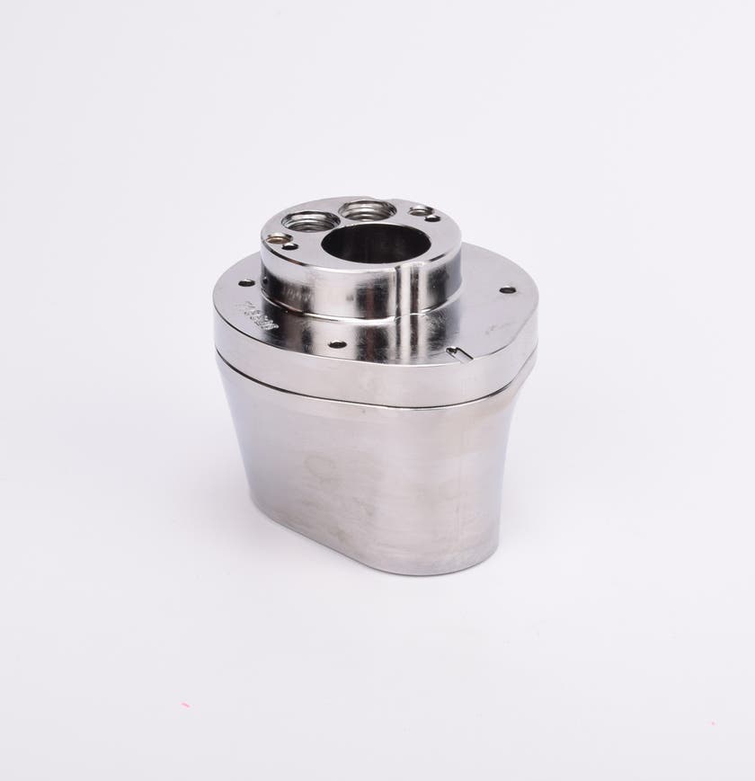 Silverfärgad metallkropp med rundad bas och flera hål på ovansidan.