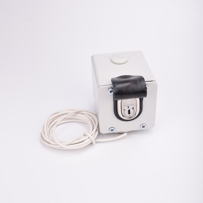 Vit kubformad nyckelbrytare med en nyckelcylinder som syns under ett svart lock, samt tillhörande vit kabel ihoprullad intill.