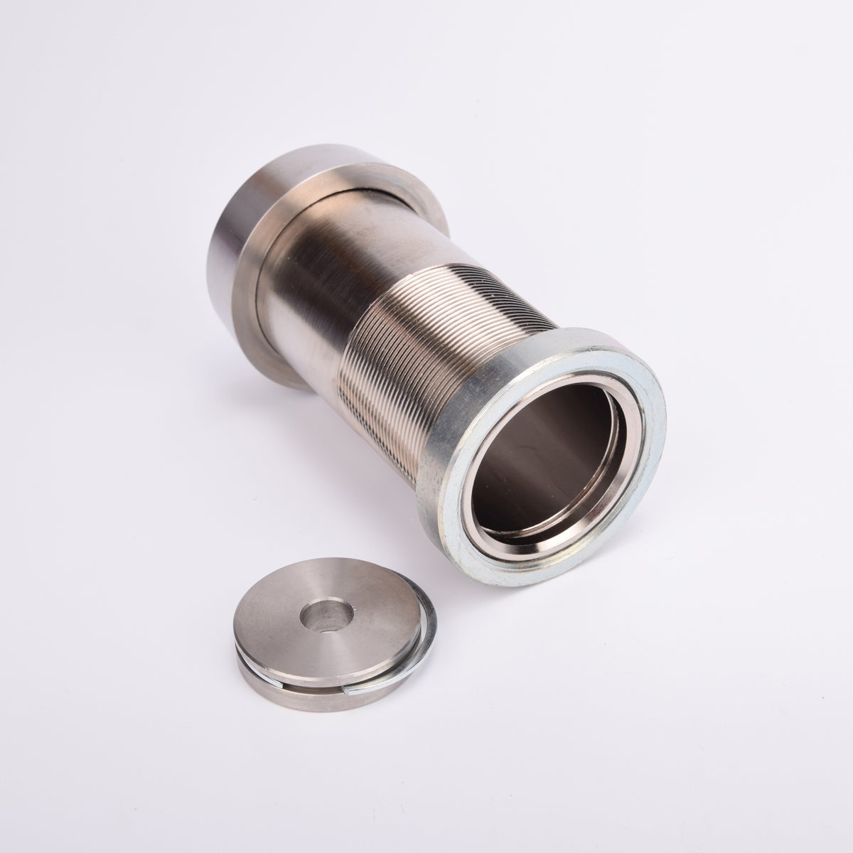 Cylindrisk silverfärgat nyckelfacksrör samt ett runt lås och en rund bricka.