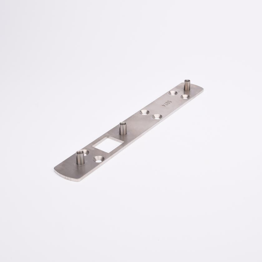 Lång rektangulär metallplatta med tre cylindriska stift, fyrkantig öppning.