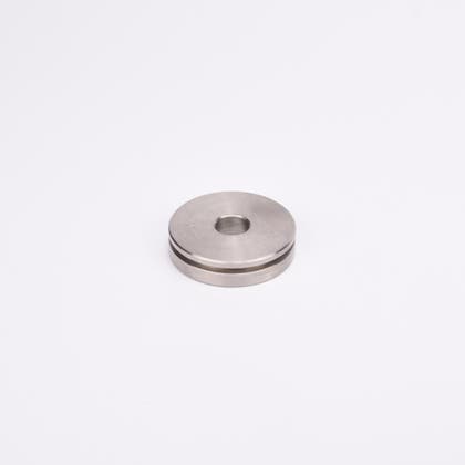 Rund metallskiva med centralt hål och spår längs med kanten.