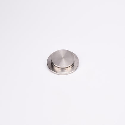 Rund entrélock i borstat rostfritt stål med platt ovansida och lätt upphöjd mitt.