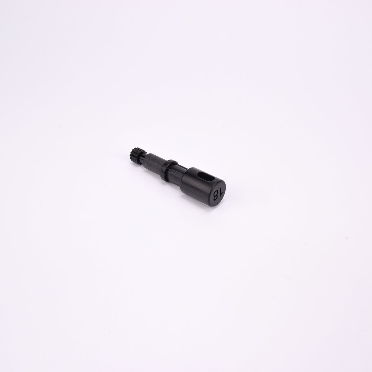 Svart användarpegg med cylindrisk form och flera sektioner med olika diameter. Ena änden är ihålig med ett avlångt spår, medan den motsatta änden har en räfflad yta.