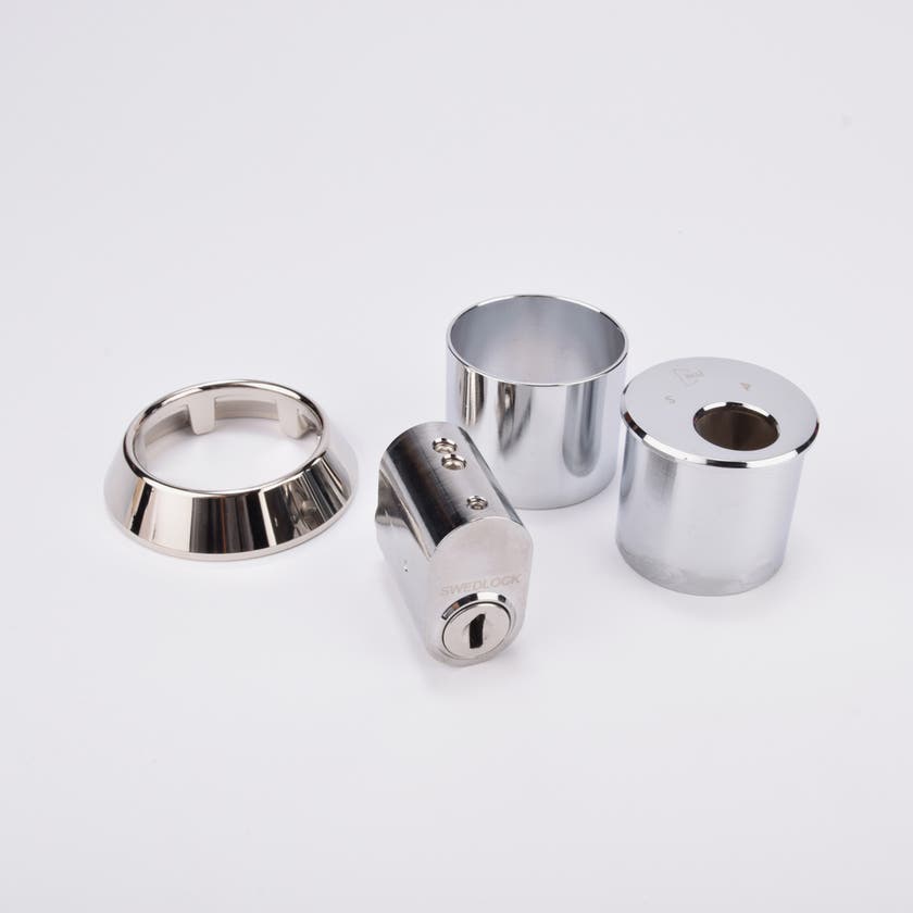 Låssats i krom med cylinder och tre runda täckhylsor.