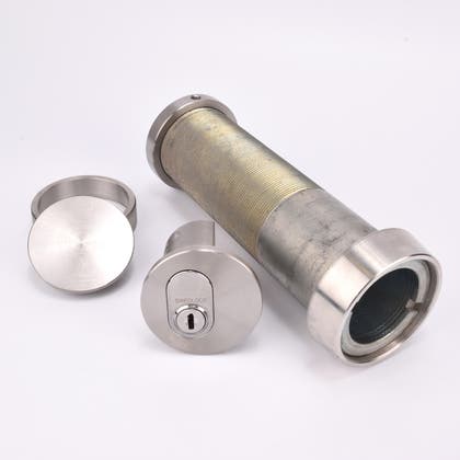 Cylindrisk silverfärgat nyckelfacksrör samt ett runt lås, en rund bricka och en rund ring.