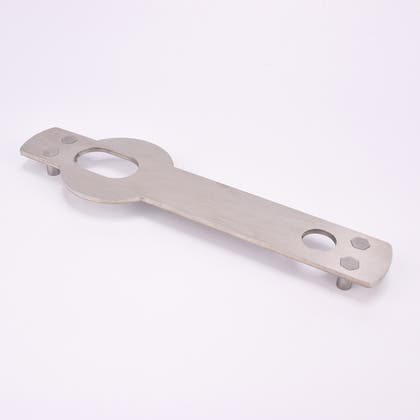 Monteringsplåt i metall med ett ovalformathål och ett runt.