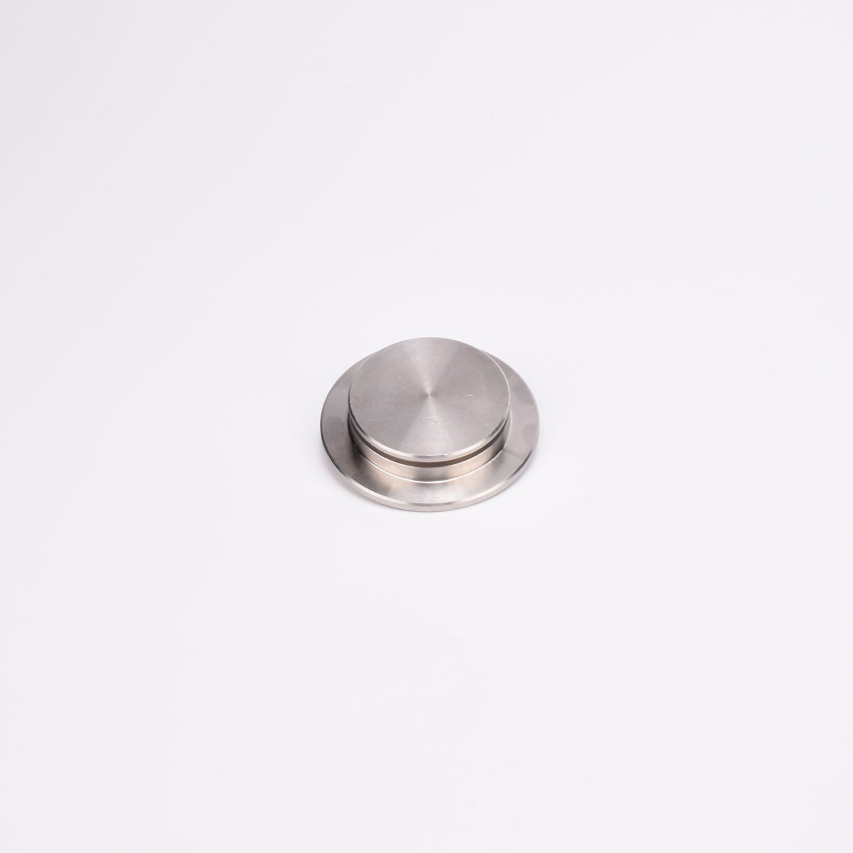 Rund entrélock i borstat rostfritt stål med platt ovansida och lätt upphöjd mitt.