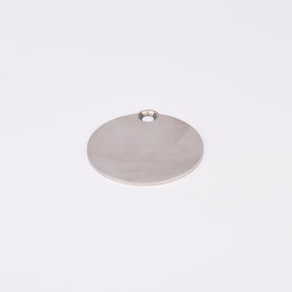 Cirkulärt väderskydd i form av en metallplatta med ett hål.