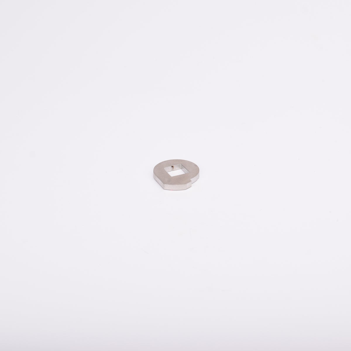 Metallbricka med cirkulär form och fyrkantigt hål i mitten.